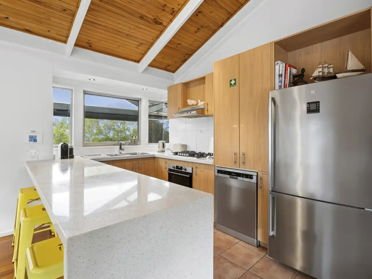Kitchen with stone bench, stainless appliances and timber cabinetry
